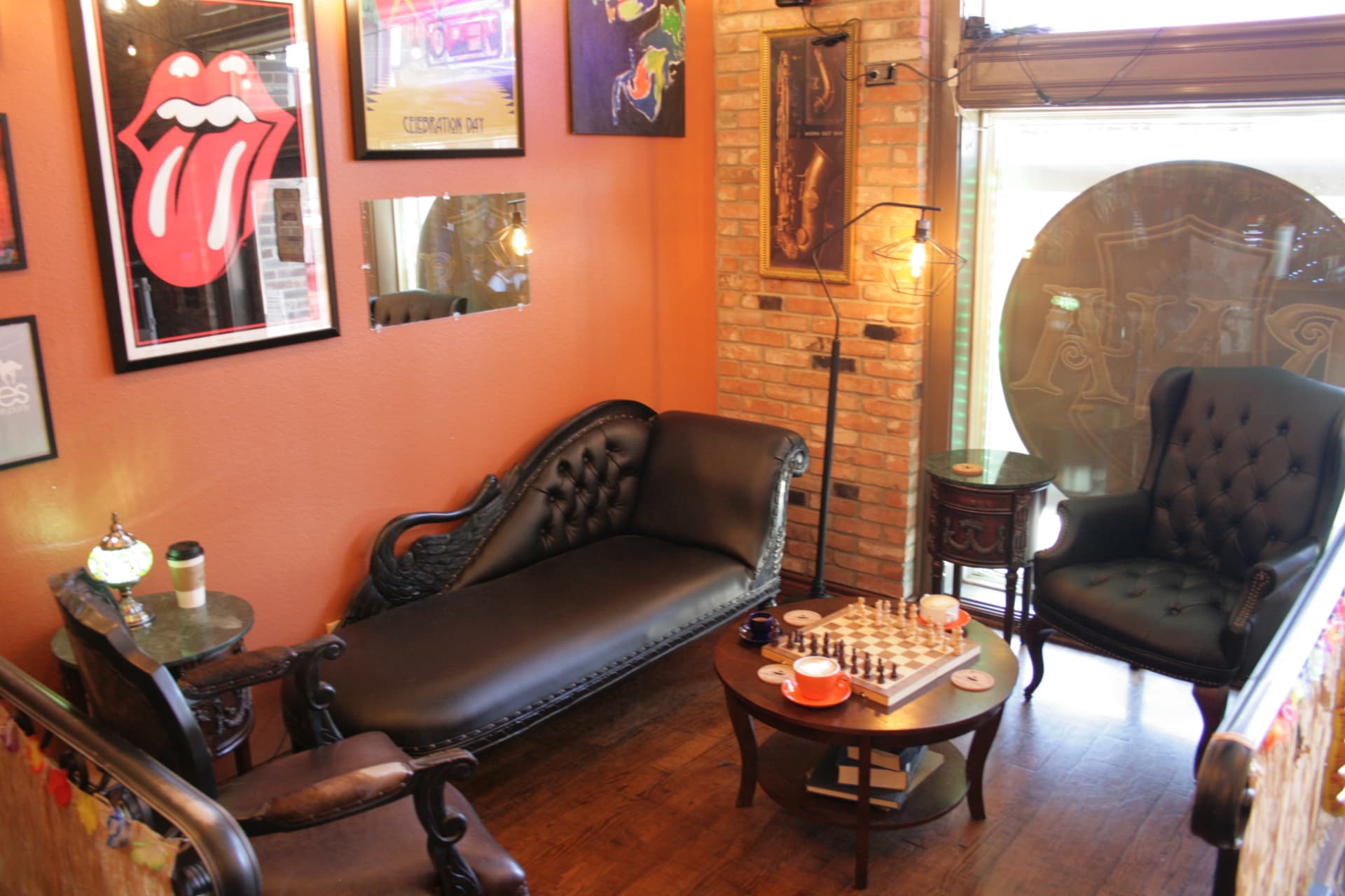 Cozy sitting nook with tufted chairs, art prints and a chess board at 1835 Coffee Company