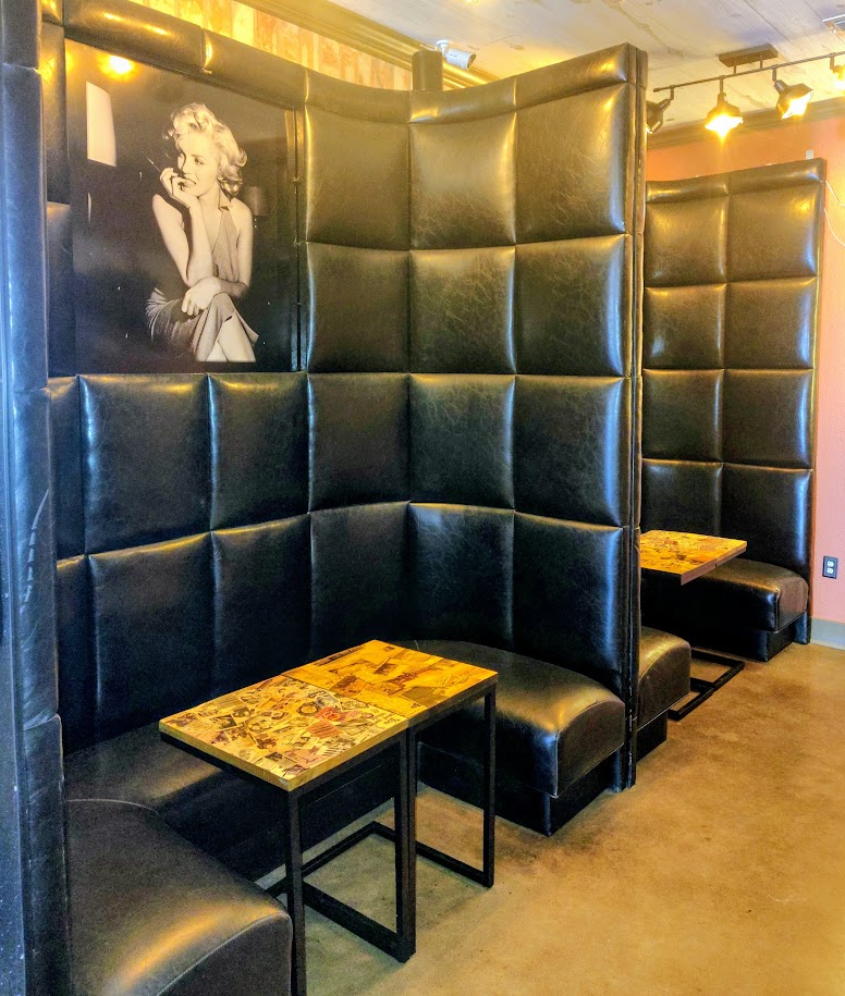 High-back black leather booths with collage-top tables